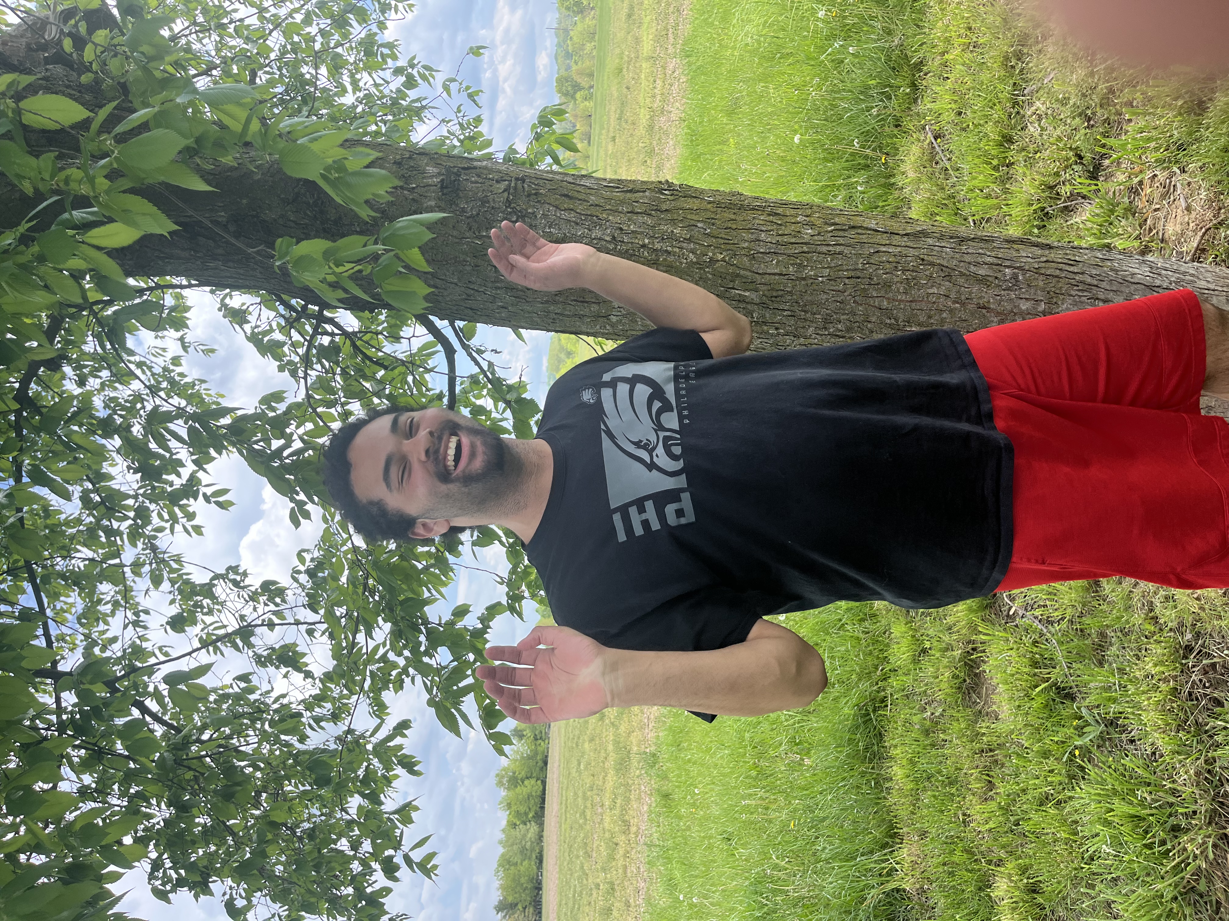 PAAL student Tristan outdoors in the community, smiling by a tree
